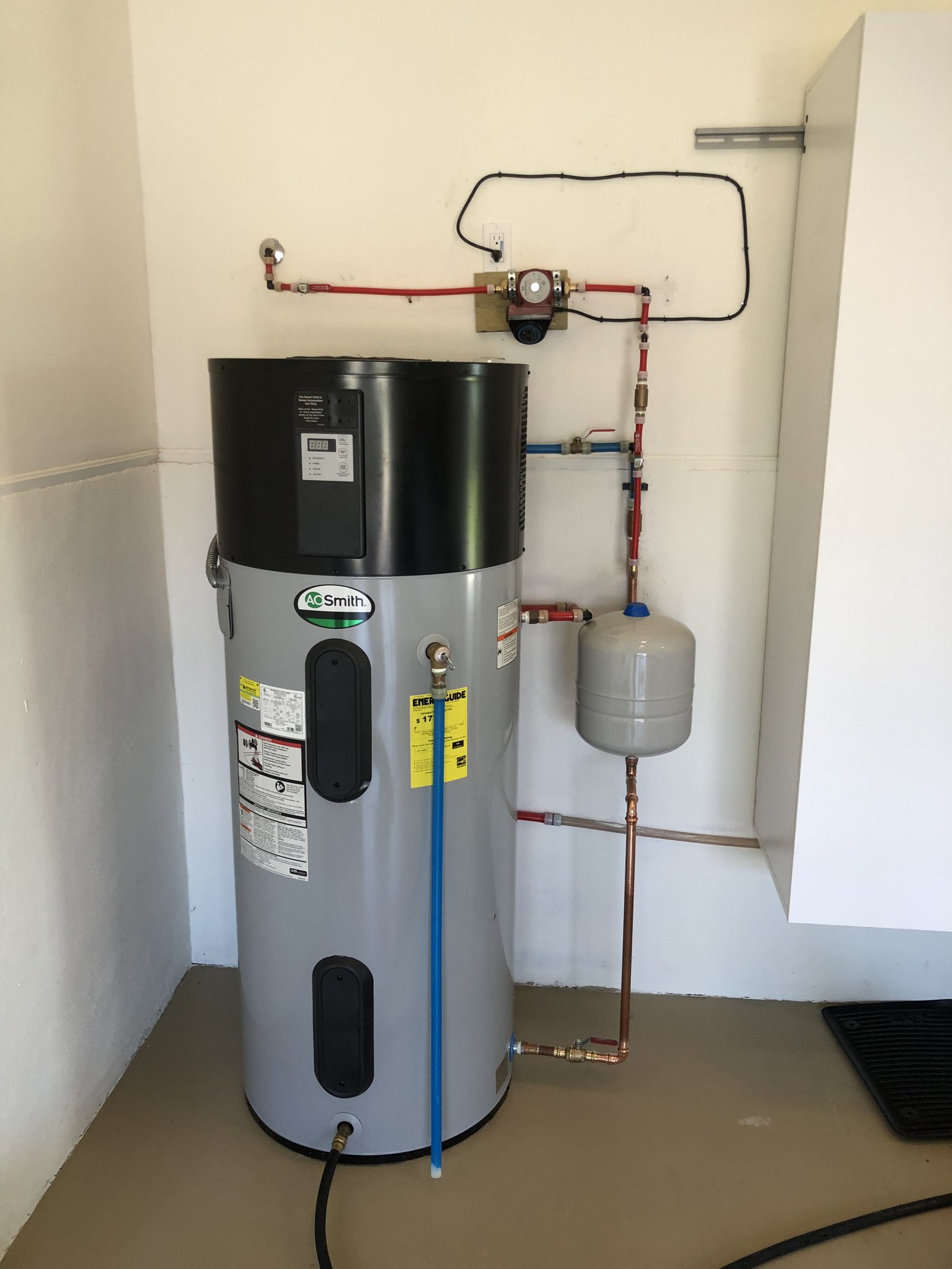 Heat-pump water heater on a stand with thermal expansion tank and new copper, installed in a Hammock Beach garage by Florida Plumbing & Inspection