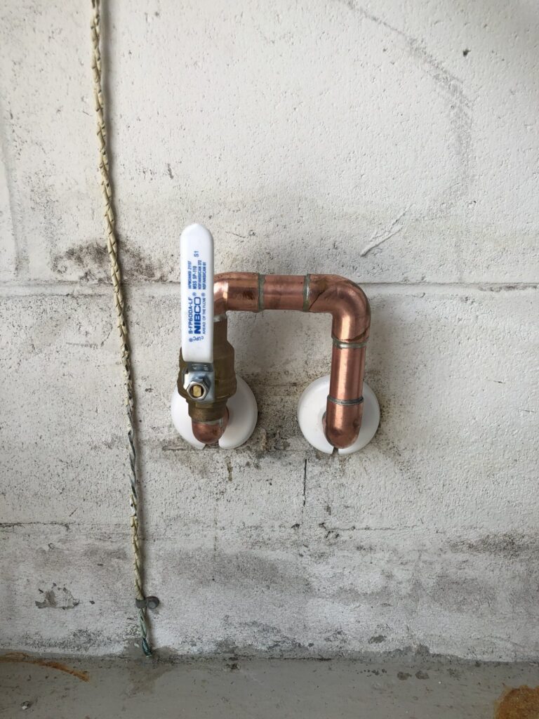 Copper water line with a white-handled ball valve on a painted block wall, low water pressure in Palm Coast, FL