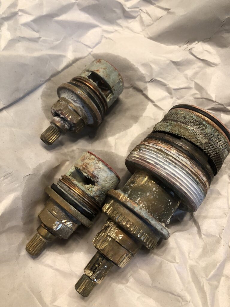Worn faucet cartridges and valve parts removed from Palm Coast faucets
