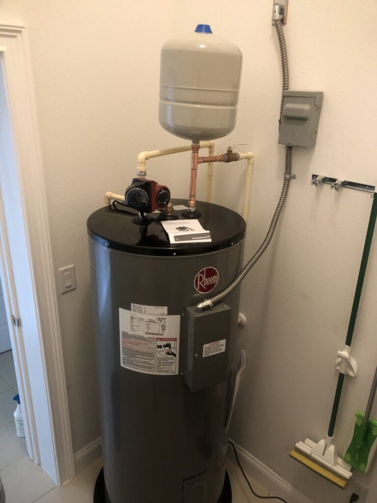 Rheem electric water heater with expansion tank on a garage wall