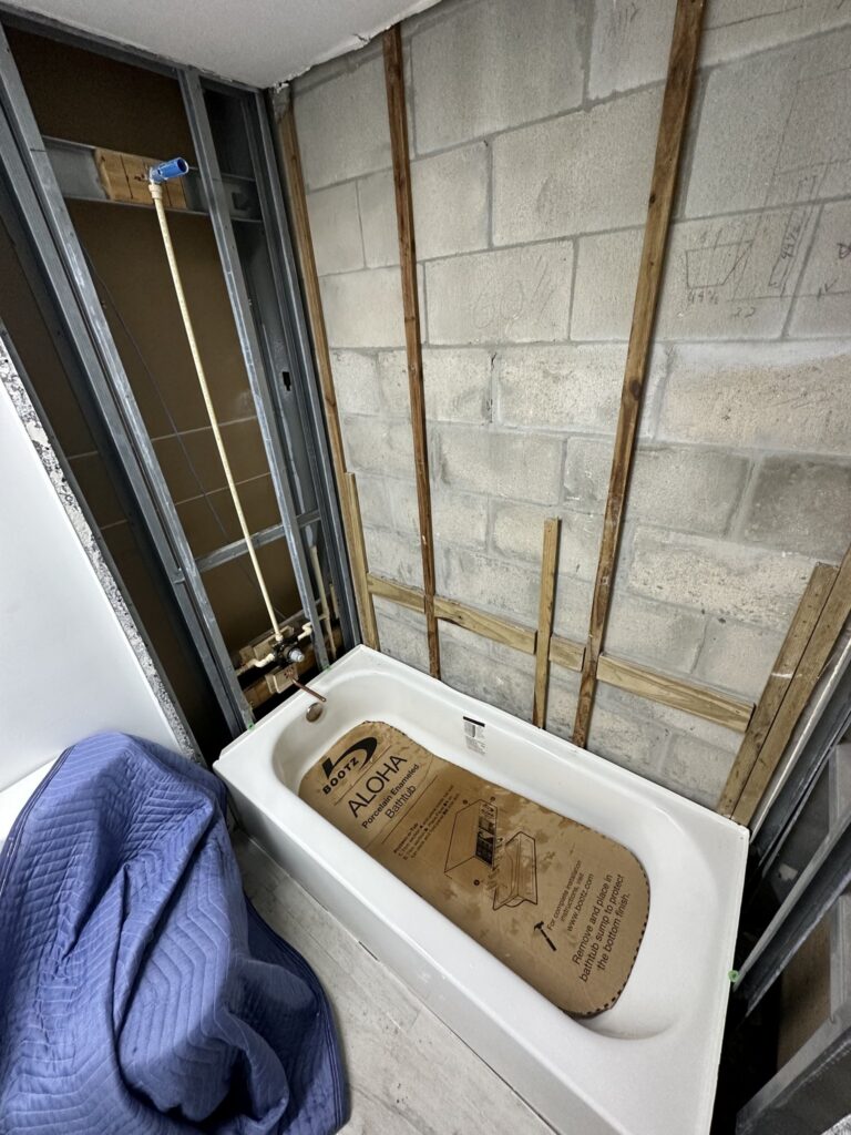 Old tub removed with rough plumbing exposed in a Palm Coast bathroom